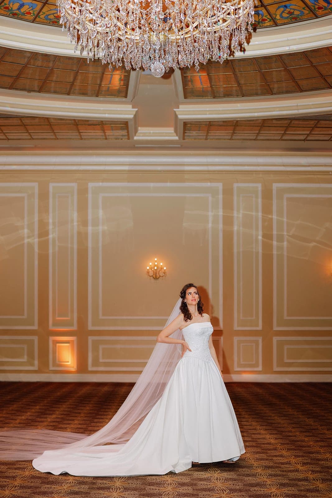 The Aurelia gown photographed beneath a ballroom chandelier
